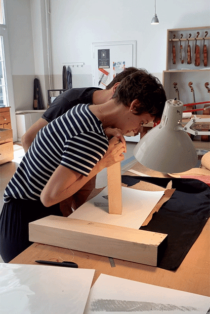 Rahel Widmer und Thiemo Schutter drucken mit Holzstücken die Key Visuals für das Geigenbauatelier Schutter Widmer Krieger